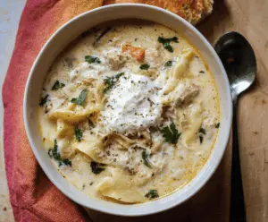 Creamy white lasagna soup in a bowl garnished with fresh basil and grated cheese, served with a spoon on a rustic wooden table