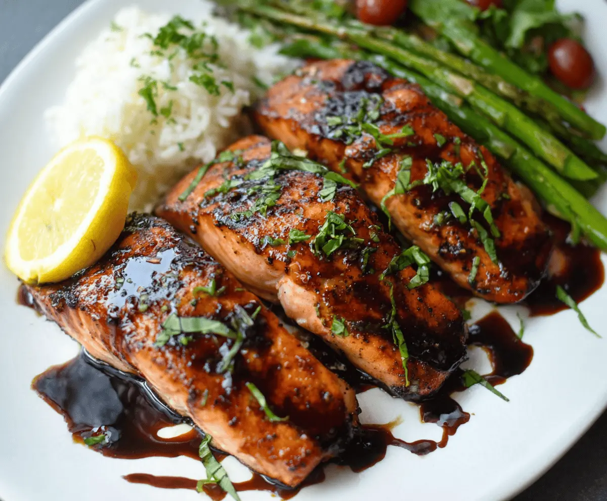 Delicious balsamic glazed salmon fillet garnished with fresh herbs on a white plate.