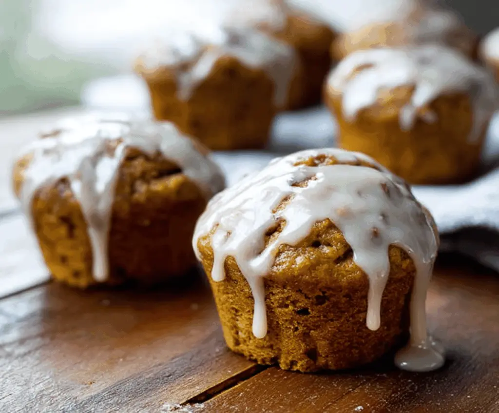 Delicious glazed pumpkin muffins with a golden-brown top and a shiny glaze, perfect for fall baking and seasonal treats.