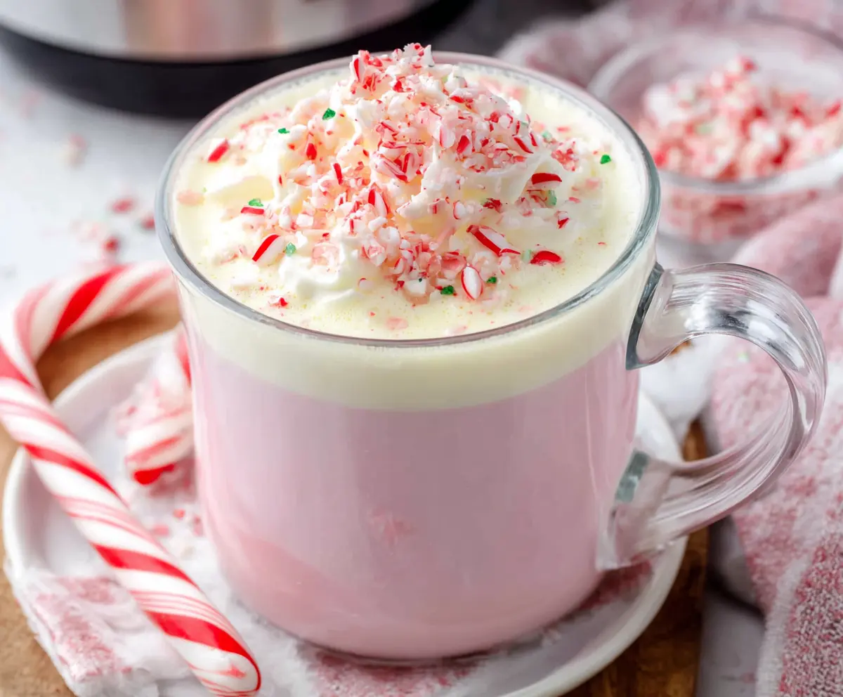 Delicious Crockpot Candy Cane White Hot Chocolate garnished with whipped cream and crushed peppermint for a festive holiday treat.