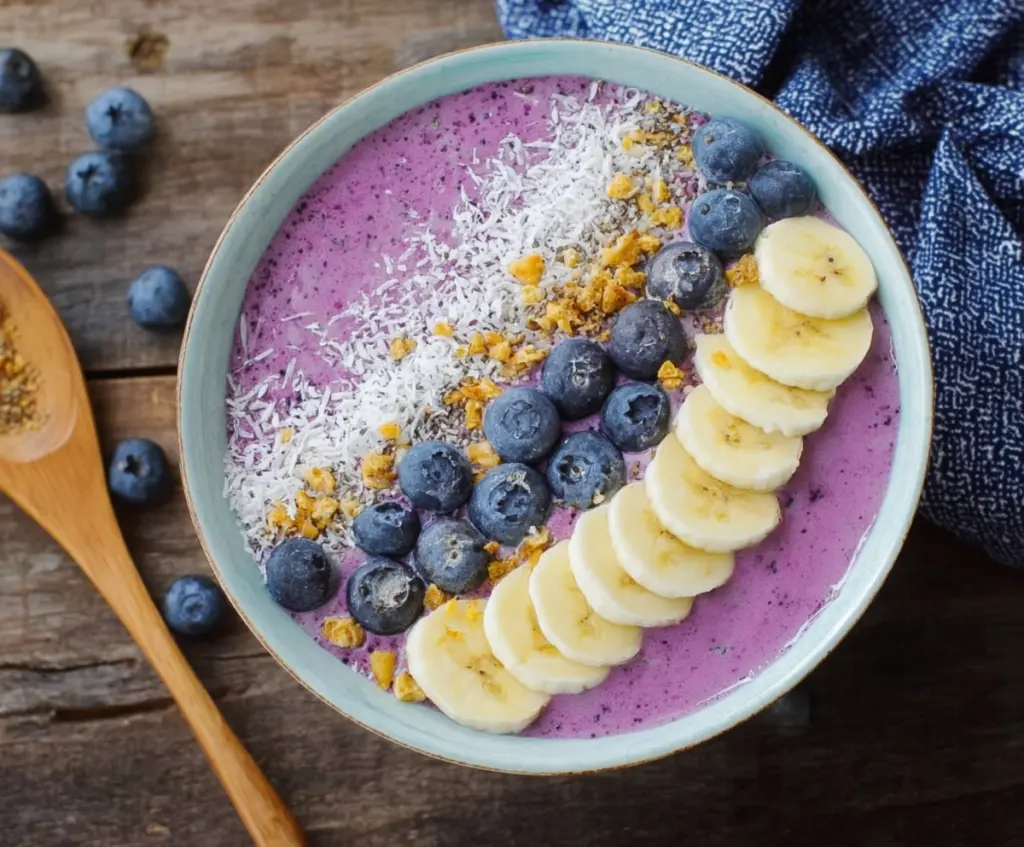 Healthy blueberry smoothie bowl topped with fresh berries and granola served in a glass bowl.