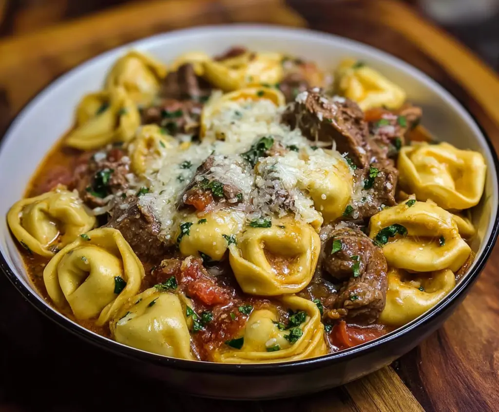 Delicious cheesesteak tortellini served on a plate with melted cheese and fresh herbs.
