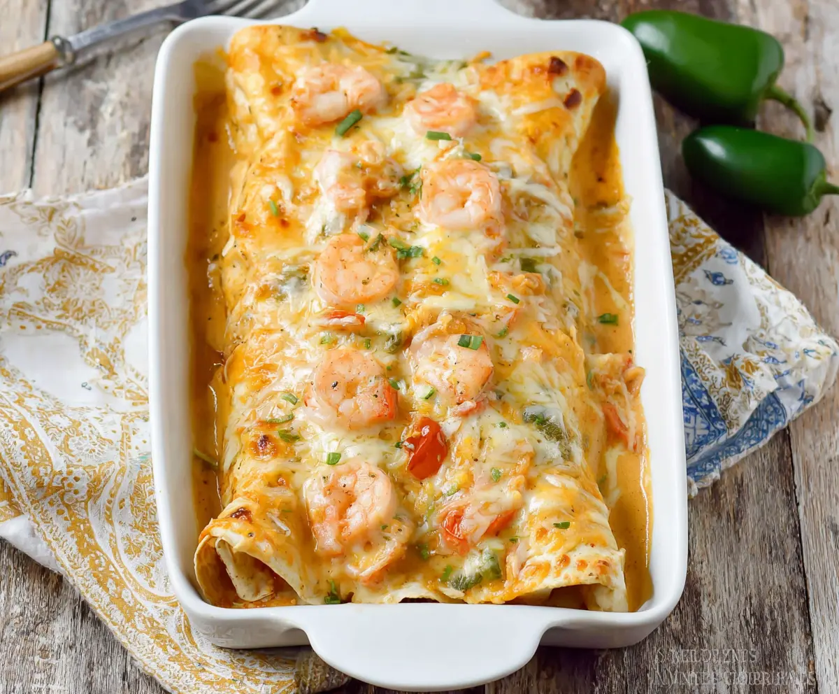 Creamy shrimp enchiladas with melted cheese and fresh cilantro in a baking dish.