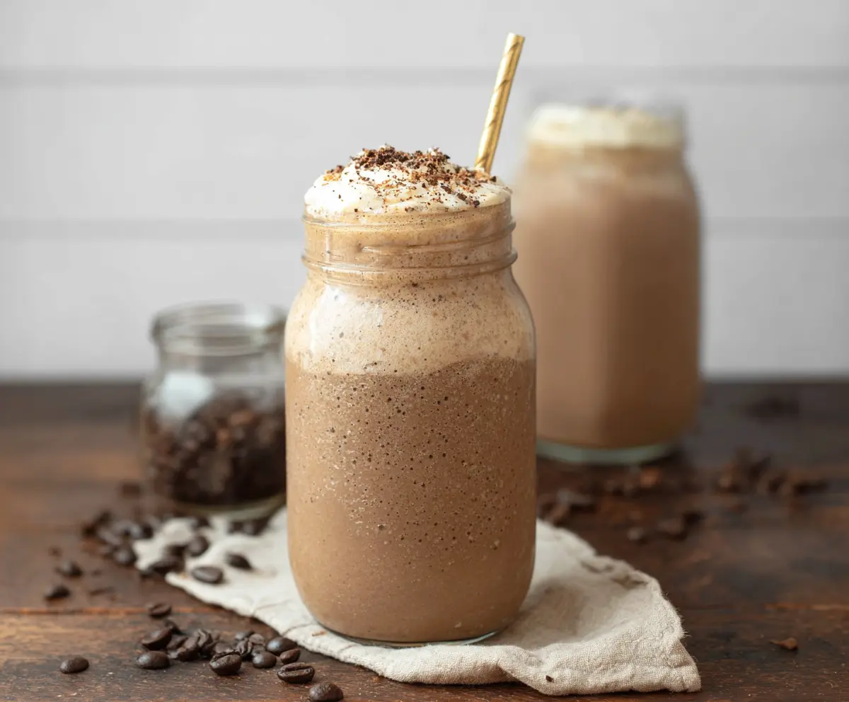 Refreshing iced coffee protein shake in a glass with ice cubes and whipped cream.
