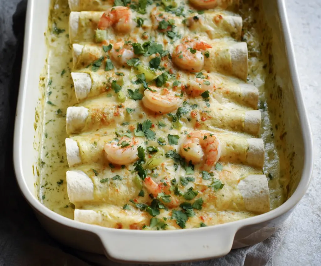 Delicious shrimp enchiladas topped with creamy poblano sauce and melted cheese on a white plate.
