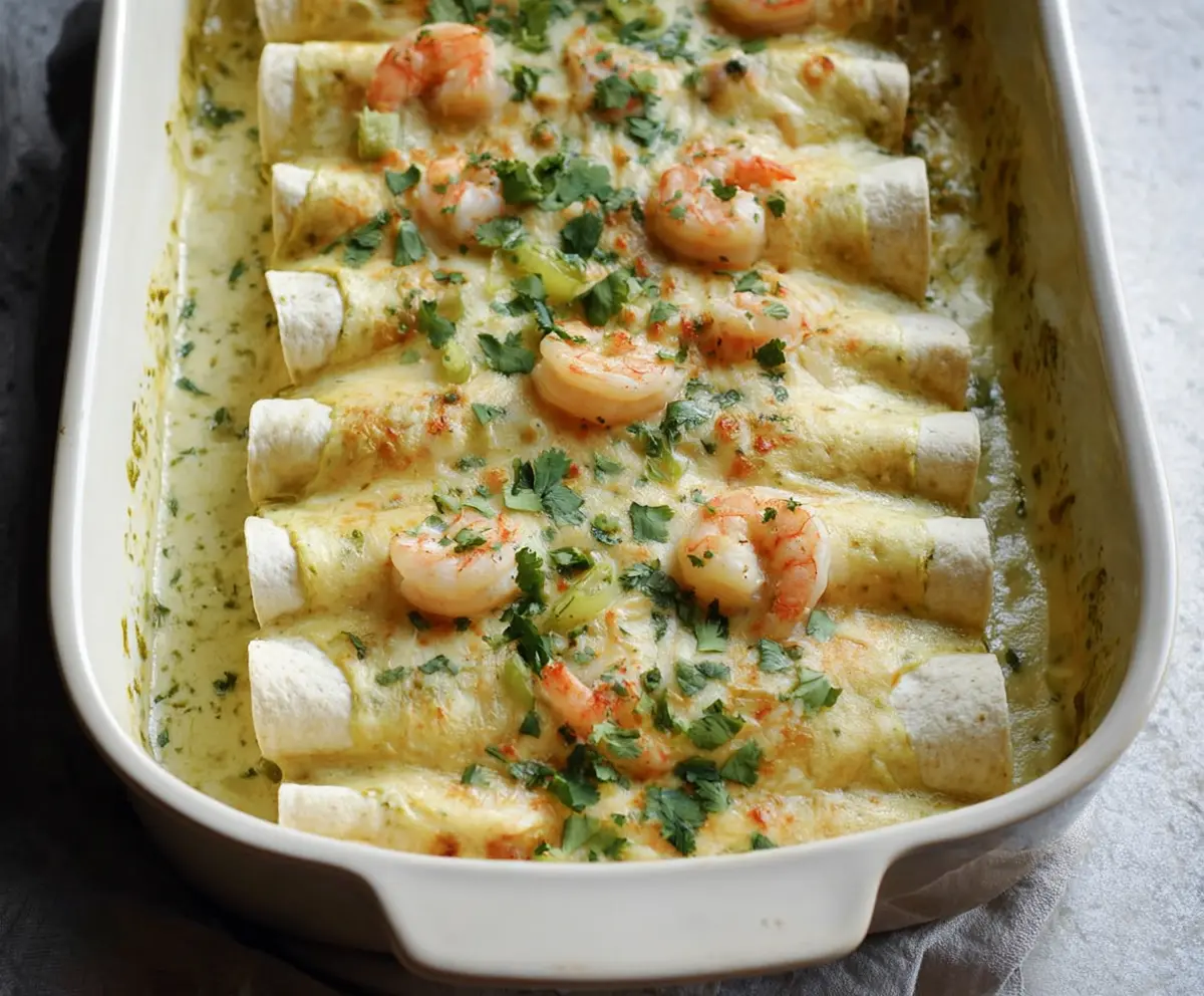Delicious shrimp enchiladas topped with creamy poblano sauce and melted cheese on a white plate.