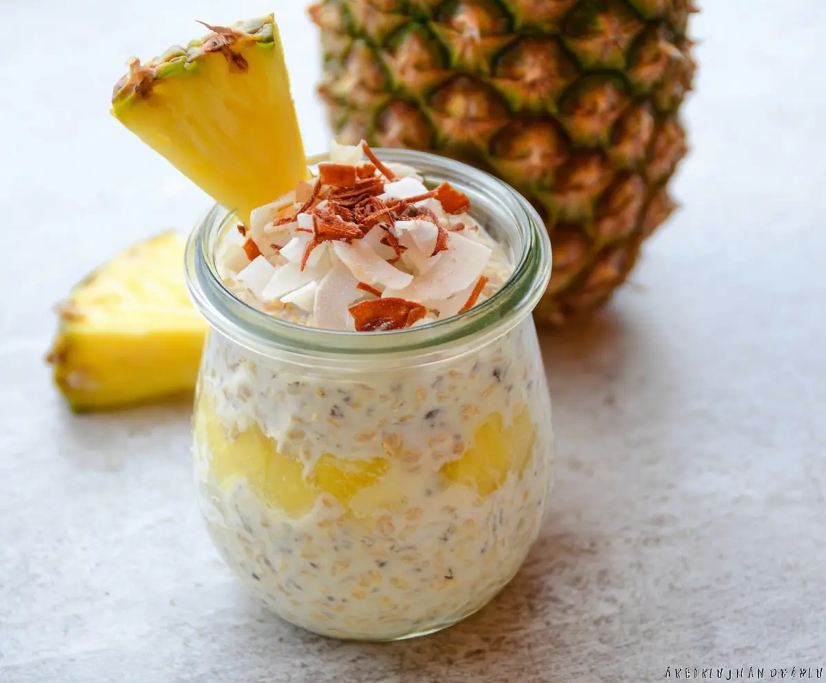 Creamy Piña Colada Overnight Oats topped with pineapple and shredded coconut in a glass jar.