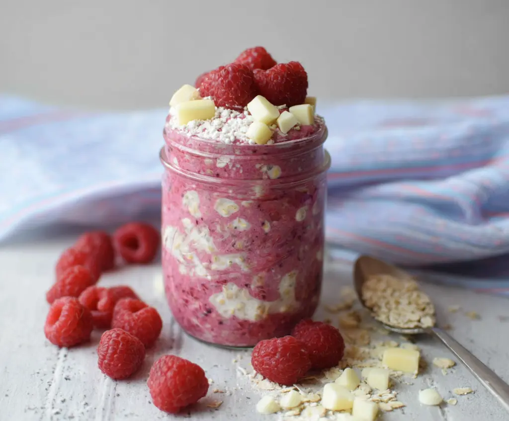 Delicious raspberry and white chocolate overnight oats in a glass jar, perfect for a healthy breakfast.