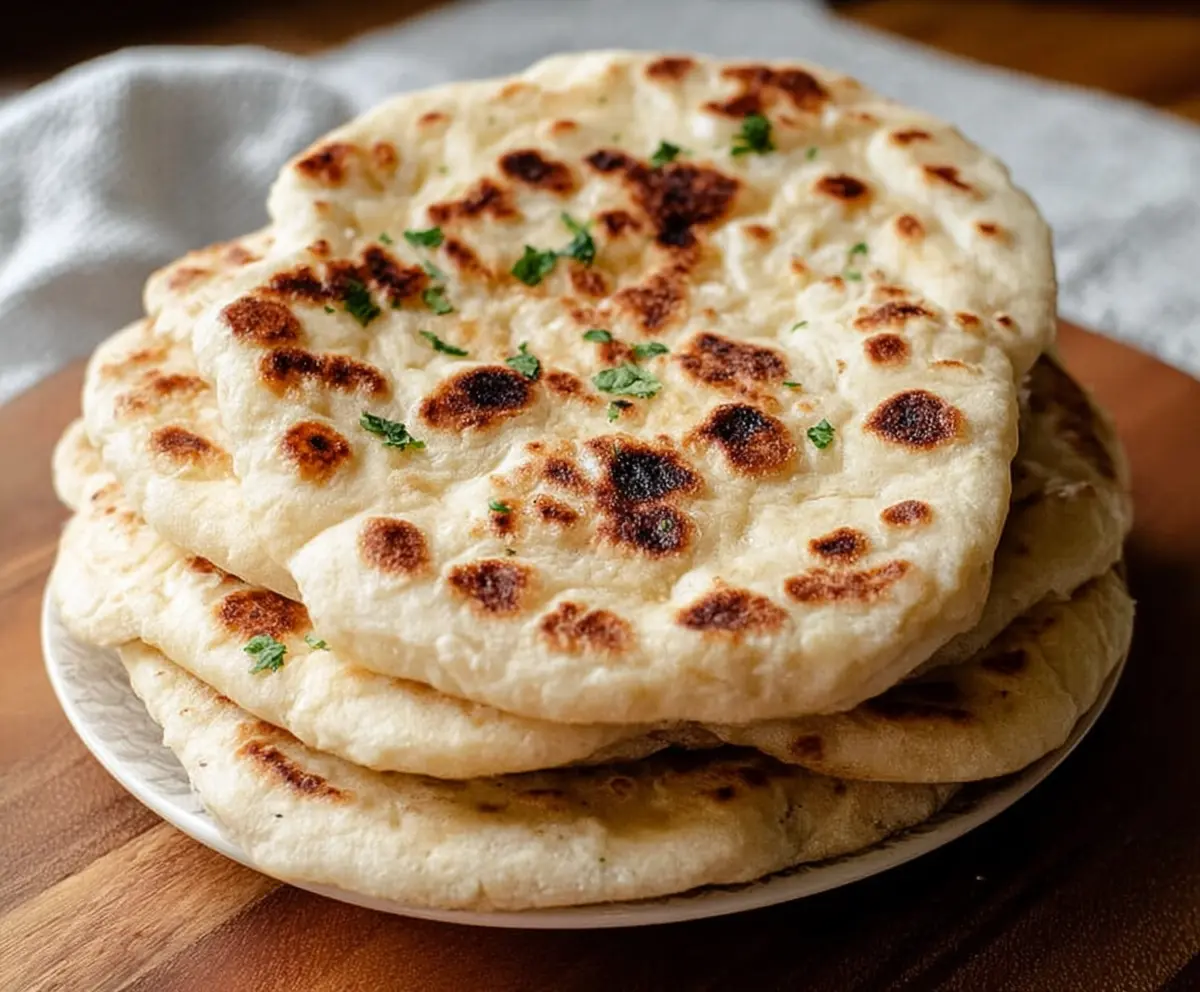 Homemade sourdough discard naan bread on a rustic wooden serving board