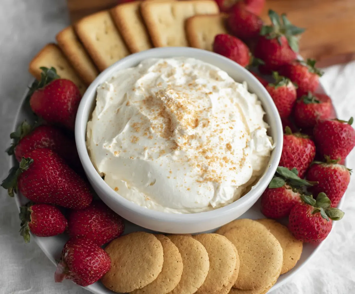 Creamy 3-ingredient cheesecake dip served with fresh strawberries on a white plate.