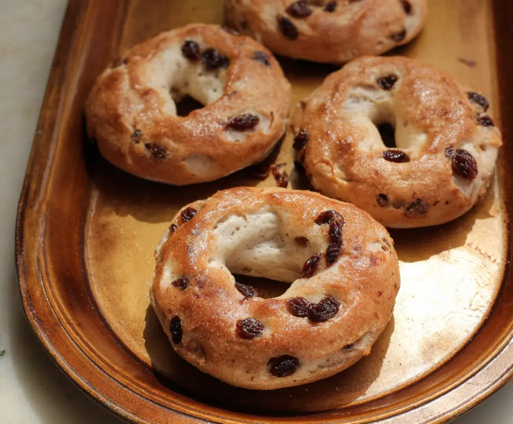Delicious cinnamon raisin yogurt bagels with a golden crust on a wooden board