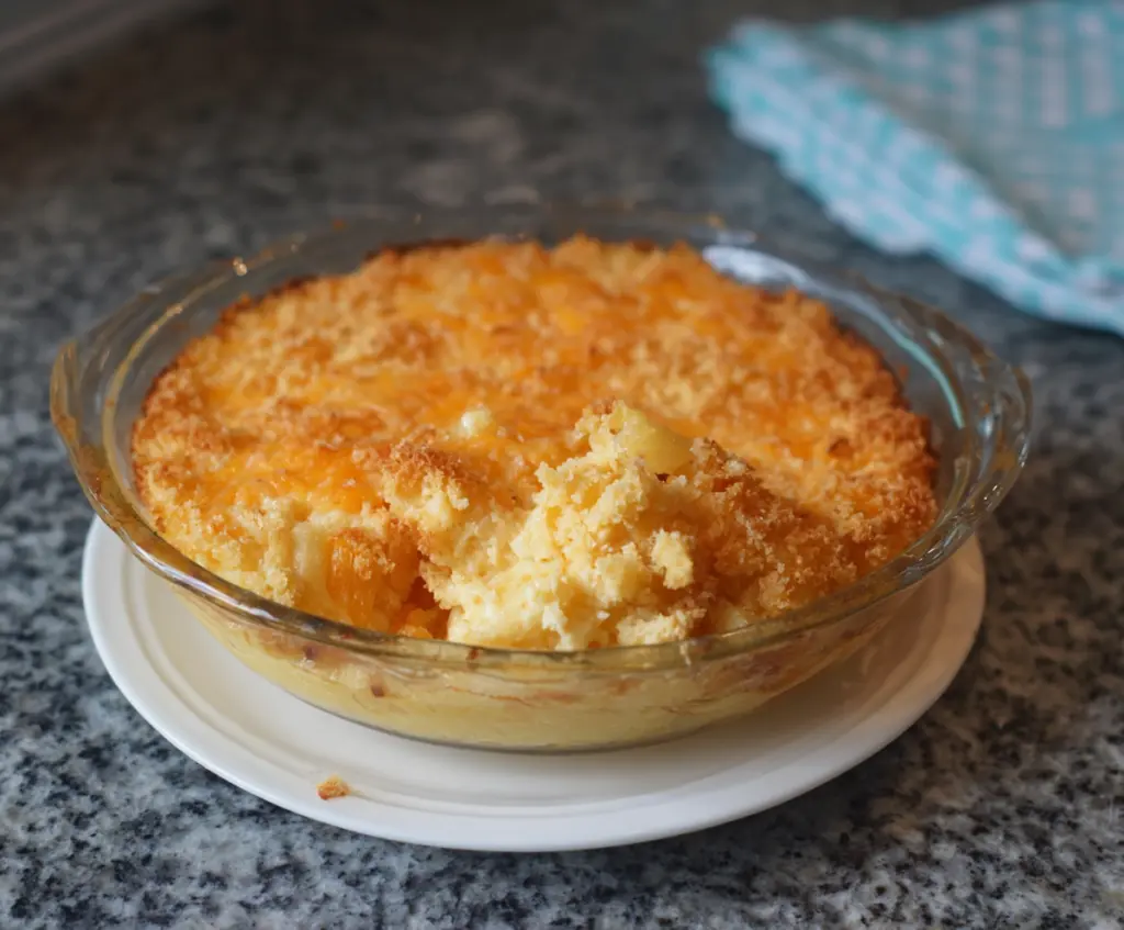 Delicious pineapple cheese casserole topped with golden melted cheese, served in a baking dish.