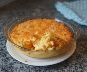Delicious pineapple cheese casserole topped with golden melted cheese, served in a baking dish.