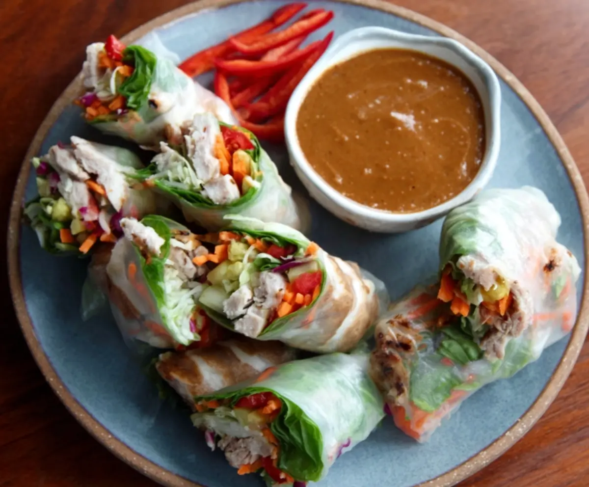Delicious pork spring rolls served with a vibrant peanut lime dipping sauce, perfect for an appetizer or light meal.
