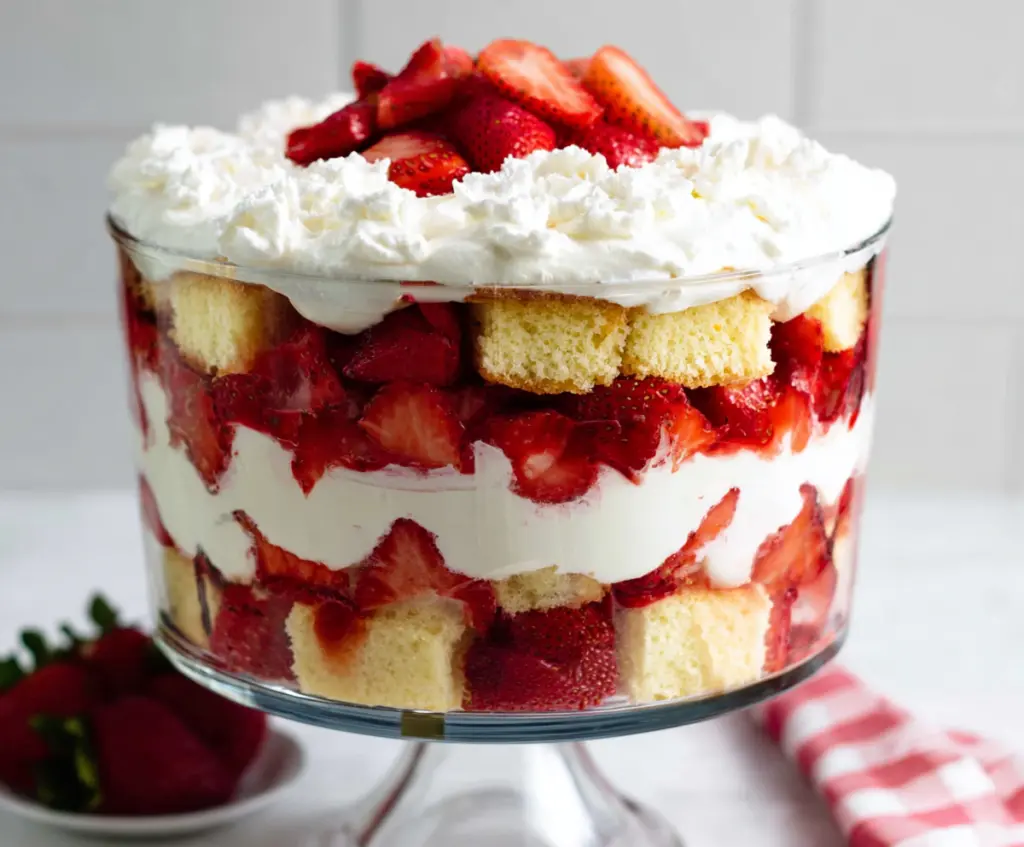 Delicious Strawberry Shortcake Trifle with layers of fresh strawberries, whipped cream, and sponge cake in a clear glass bowl.
